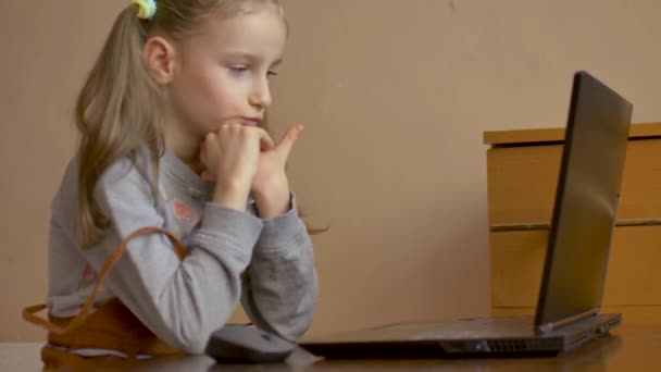 Niña seria se concentra en frente de su portátil negro mientras se centra en hacer la tarea durante la cuarentena debido a la pandemia de Coronavirus Covid-19. Educación remota — Vídeo de stock