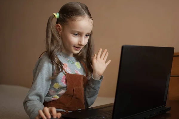 Pequena aluna está estudando em casa com seu professor usando bate-papo por vídeo em seu laptop preto por causa do auto-isolamento devido à pandemia de Coronavirus Covid-19 — Fotografia de Stock