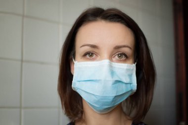 Coronavirus Covid-19 salgını. Pandemia sırasında virüsten korunmak için yüzüne cerrahi maske takan genç bir kadın.