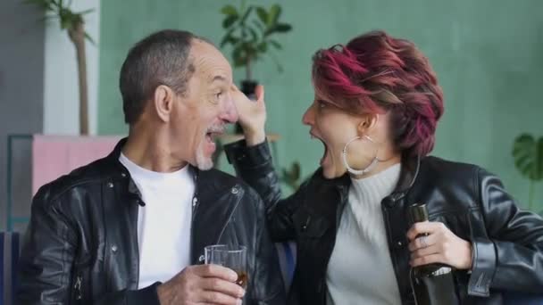 Ung fru och äldre make dricker på grund av potens problem i deras familj. Mannen håller ett glas whisky, kvinnan sitter med flaskan i handen, de skriker till varandra — Stockvideo