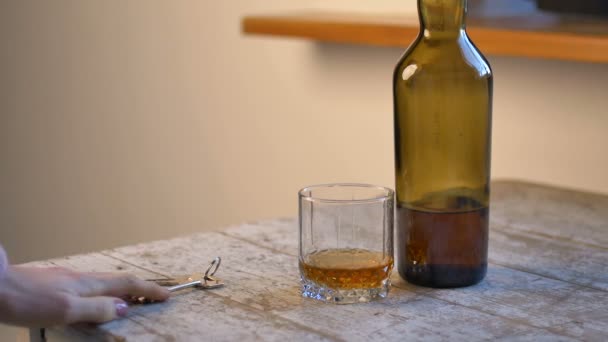 Женская рука кладет ключ на стол и берет стакан виски, чтобы выпить, алкогольной зависимости концепции — стоковое видео
