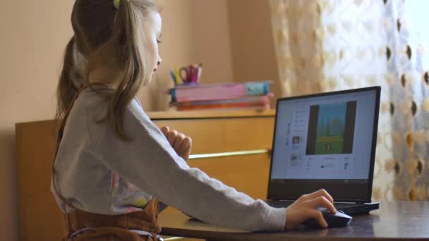 Vista posterior de una niña pequeña con dos colas de caballo sentada frente a la pantalla de su portátil negro y estudiando en casa debido al autoaislamiento debido a Coronavirus Covid-19. Educación remota — Vídeos de Stock