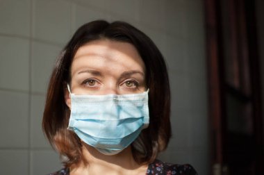 Coronavirus Covid-19 salgını. Pandemia sırasında virüsten korunmak için yüzüne cerrahi maske takan genç bir kadın.