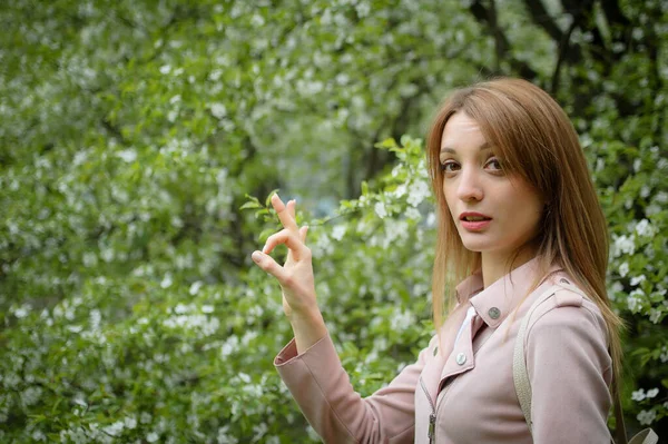 Ξανθιά γυναίκα δείχνει εντάξει στο ανθισμένο δέντρο φόντο στον κήπο κατά τις αρχές της άνοιξης. Έννοια διακοπής αλλεργίας — Φωτογραφία Αρχείου
