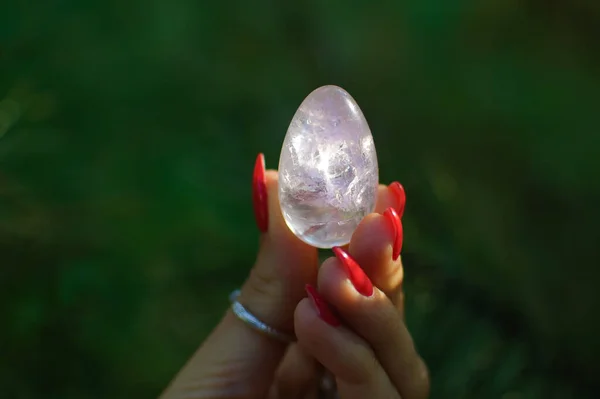 Mão feminina com ovo de yoni de quartzo ametista transparente para vumfit, imbuilding ou meditação. Brilhando ovo de cristal em mãos no céu e nascer do sol fundo ao ar livre. Conceito de saúde das mulheres . — Fotografia de Stock