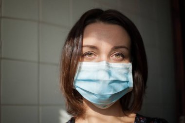 Coronavirus Covid-19 salgını. Pandemia sırasında virüsten korunmak için yüzüne cerrahi maske takan genç bir kadın.