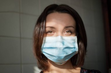 Coronavirus Covid-19 salgını. Pandemia sırasında virüsten korunmak için yüzüne cerrahi maske takan genç bir kadın.