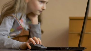 Küçük çocuk bir bilgisayar faresini dizüstü bilgisayarın arka planında tutuyor. Evde kalırken karantina ve izolasyon süresince uzak çevrimiçi eğitim