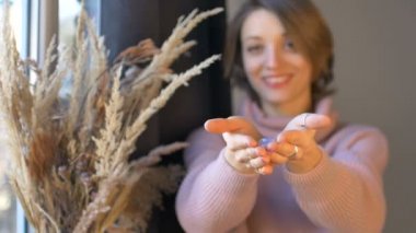 Kadının elinde şeffaf menekşe ametist taşından yapılmış yoni yumurtası var. Pencere kenarında dikenli vazoyla duruyor. Kadın sağlığı konsepti, vumfit, imbuilding veya meditasyon