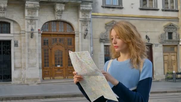 Kobieta jest zagubiona w starym europejskim mieście patrząc na mapę i szukając kierunku wczesnym rankiem na starożytnym placu. — Wideo stockowe
