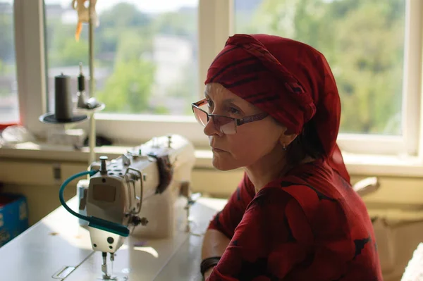 La mujer está usando la máquina de coser para coser la máscara facial durante la pandemia del coronavirus. Sastrería doméstica debido a la escasez de materiales médicos . — Foto de Stock