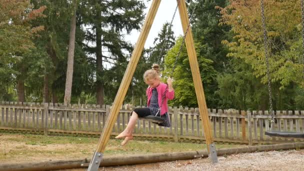 Kis gyermek szőke mezítlábas lány szórakozás egy hinta szabadban a nyári napsütéses napon játszótéren a kertben, boldog gyermekkori koncepció — Stock videók