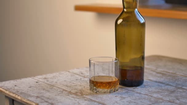La mano femenina con manicura rosa toma una copa de whisky de la mesa, concepto de adicción al alcohol. — Vídeo de stock
