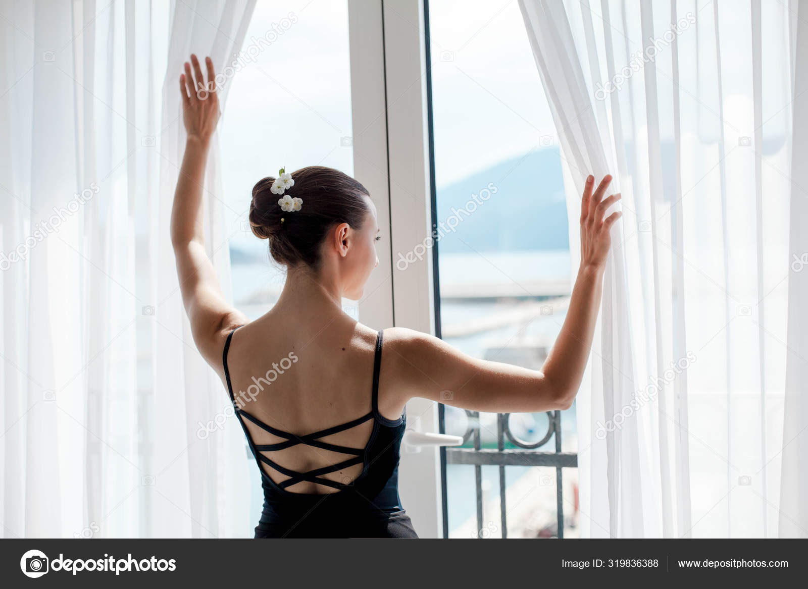 Girl is opening big window with view of sea and mountains. Ballerina has break in dance workout in ballet class room. Dancer stands Stock Photo ©Maryna_Andrejchenko 319836388