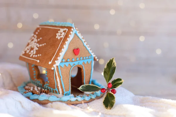 Christmas gingerbread house, decorations on wooden and knitted background with glares.