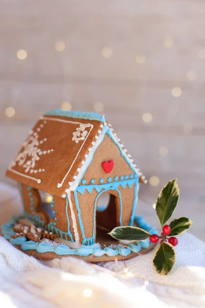 Christmas gingerbread house, decorations on wooden and knitted background with glares. Handmade sweets