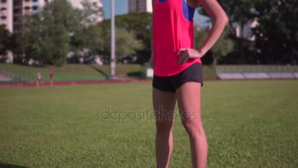 Câmera lenta de asiático feminino corredor no herói pose no meio do campo — Vídeo de Stock