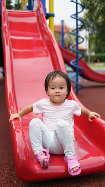 Asiático chinês criança deslizando para baixo em um playground — Fotografia de Stock