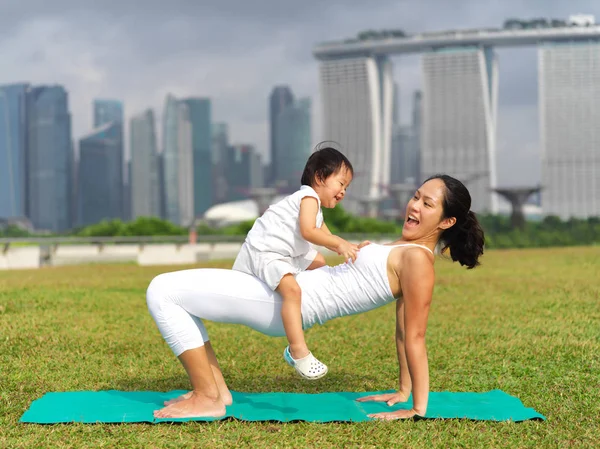 Asiática china mujer practicando yoga al aire libre con joven bebé niña —  Fotos de Stock