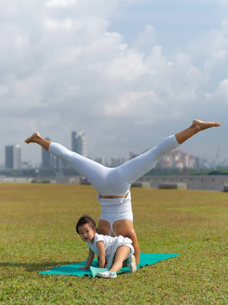 Asiático chinês mulher praticando ioga ao ar livre com jovem bebê menina — Fotografia de Stock