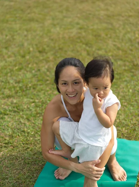 Asiática china mujer practicando yoga al aire libre con joven bebé niña —  Fotos de Stock