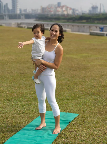 Asiatisk kinesisk kvinna utövar yoga utomhus med ung flicka — Stockfoto
