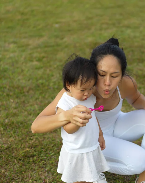 Aziatische chinese vrouwelijke bovenliggende blowing bubbles met babymeisje — Stockfoto