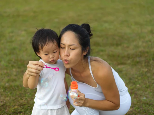 Asiático chinês feminino pai soprando bolhas com bebê menina — Fotografia de Stock