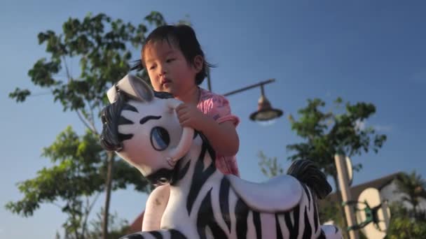 小亚洲华人女孩玩摇滚斑马玩具在操场上慢动作 — 图库视频影像