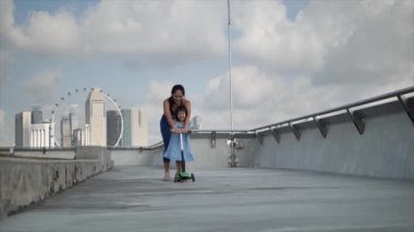 Asyalı Çinli anne ve kız yavaş çekimde kaykayla oynuyorlar.