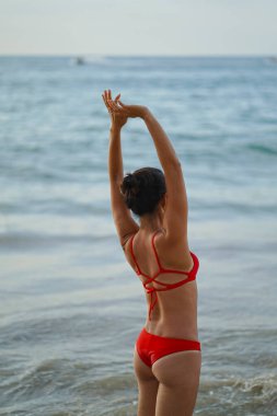 Sahilde sırtı kameraya dönük yalnız bir Asyalı Çinli kadın.