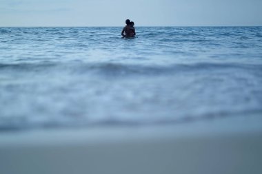 Asyalı Çinli kadın kızıyla kumsalda vakit geçiriyor.