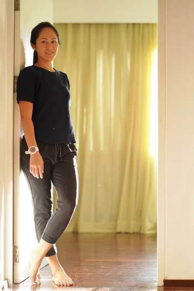 Asian Chinese woman standing at bedroom door smiling