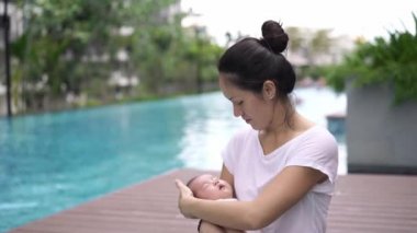 Asyalı genç anne ve yeni doğmuş çocuğu yüzme havuzunda.