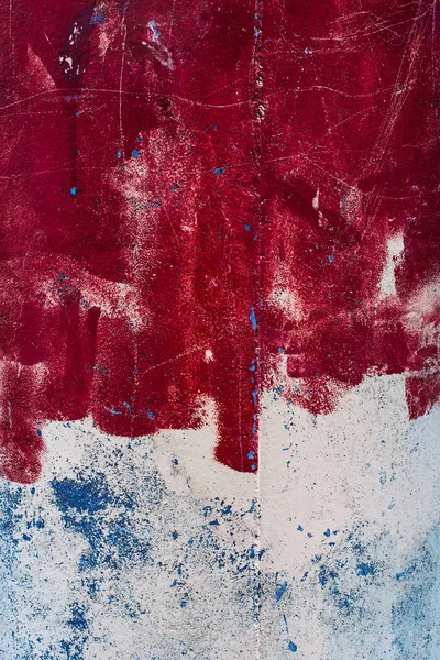 Red blue white brush strokes paint an abstract picture of a close-up. Colored design lines texture of layers of paint on the wall surface. Scratches and small patches of graffiti adorn the canvas picture.