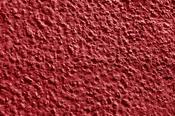 Red wall texture pattern of circular shapes on the whole surface. A piece of concrete with patches of plaster close up. Juicy red abstract background.