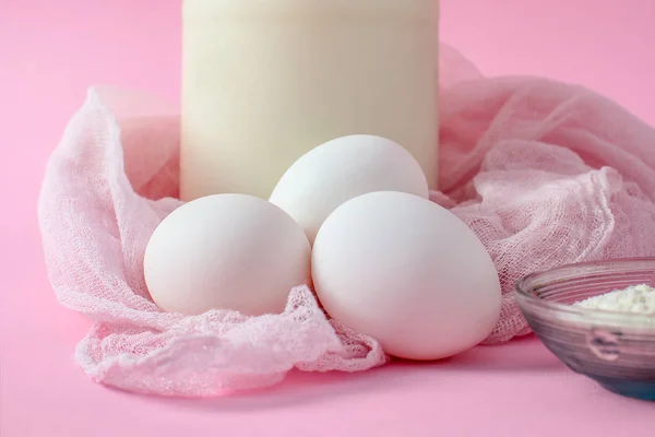 ベーキング - のための原料卵、牛乳、小麦粉をガラス容器。Horzontall。ピンクの背景のピンクの綿生地 — ストック写真