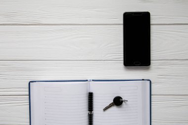 İş Not, cep telefonu, anahtar ve para üzerinde beyaz ahşap arka plan belirleme 