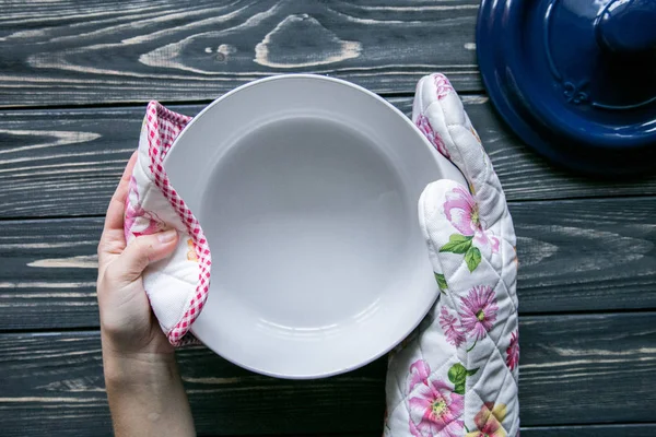 Mutfak Tekstil ve koyu gri ahşap arka plan ellerde bir pot dişinin kümesi 