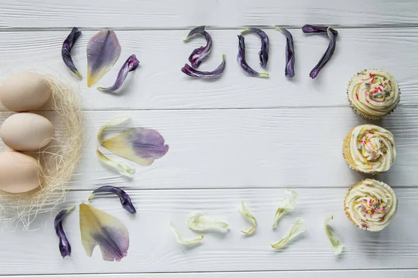 Великодня композиція з яйцями і сушеними фіолетовими пелюстками квітів. Надпис 2017 року, місце для тексту — стокове фото