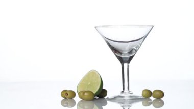 Martini vermut ya da likör bir cam içine dökülür. Limon ve zeytin masada.
