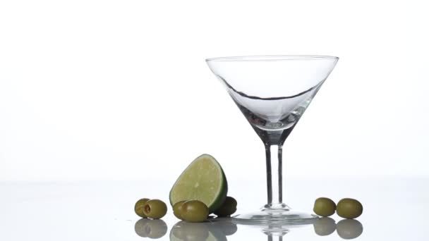 Vermouth Martini ou liqueur est versé dans un verre. Chaux et olives sur la table . — Video