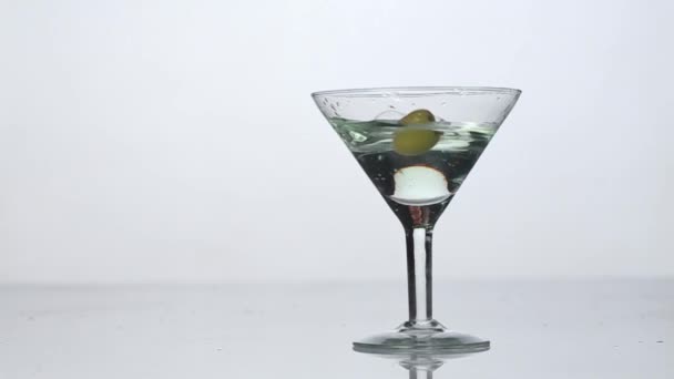 Slow motion. Vermouth is pouring into a glass. An olive falls into a glass and disappears on the end of video — Stock Video