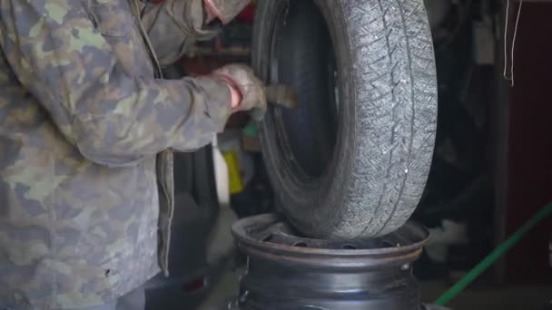 Un professionnel de l'entretien automobile prépare un pneu pour le remplacement — Video