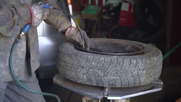 Egy férfi autógumit pumpál egy autószerelő műhelyben. — Stock videók