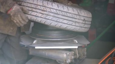 Tamirci aracın lastiğini patlattı. Lastik değiştiricinin yardımıyla alaşımlı tekerden lastik çıkarma işlemi. Kış lastikleri