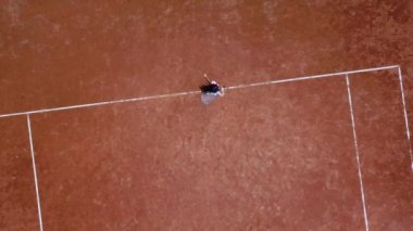 Küçük kız tenisçi tenis kortunda durur ve gövdeyi farklı yönlere çevirir.