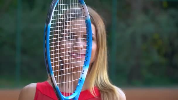 Una chica entrena para jugar al tenis en la cancha marrón — Vídeos de Stock