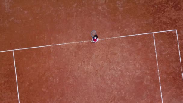 Little girl tennis player standing on tennis court waving hello to camera — ストック動画