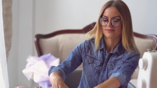 Couturière blonde en atelier de couture travaille avec du tissu à table — Video